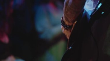 Canlı performans sırasında müzisyenlerin gitarına yakın çekim. Gençler kalabalığının önünde grup takılıyor. Küçük bir kulüpte müzik gösterisi, özgürlük ve coşku ortamı. Boş zaman kavramı, yaşam tarzı.