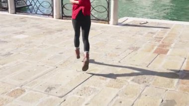 Ateşli esmer tilki deniz kenarında romantik bir yürüyüş için işaret ediyor. Venedik 'in dar sokaklarında yürüyen çizgili pançolu şık Asyalı kadın. Seyahat kavramı.