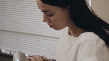 Kadın hasta yüzü üzerinde cihaz üzerinde çalışan ve kaldırma prosedürü uygulayan güzellik uzmanına yakın çekim. Kozmetoloji ofisinde yüz ameliyatı.