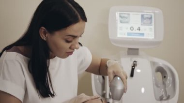 Güzellik muayenehanesindeki kozmetik uzmanı özel cihazlı kadın hasta üzerinde kaldırma işlemi yapıyor. Kadın yüzündeki düzeltme çizgileri boyunca ilerleyen bir uzman.