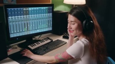 Gitar çalan ve sentezleyen genç bir kadın eşitleyici programı kullanarak müzik yaratıyor. Yaratıcılık sürecinin tadını çıkaran bir kız. Ev kayıt stüdyosunda hafif sinemada bayan müzisyen şarkısı.