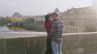 Genç aşıklar öpüşüyor ve birlikte vakit geçiriyorlar. Tatlı çiftin, eski Avrupa kasabasında, günbatımı köprüsünde romantik bir randevusu var..