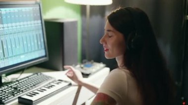Gitar çalan ve sentezleyen genç bir kadın eşitleyici programı kullanarak müzik yaratıyor. Ev kayıt stüdyosunda bayan müzisyen şarkısı.