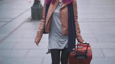 Çekici genç kadın gezgin ellerinde bavulla şehir caddesinde yürüyor. Hipster kız turist tatili sırasında eski şehir merkezini keşfediyor. Macera, gezi ve turizm konsepti