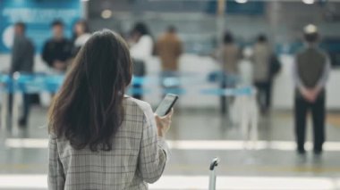 İş için seyahat eden, uçuş için kayıt bekleyen bir kız. Havaalanı terminalinin ortasındaki genç iş kadınının arka görüntüsü. İş gezisi sırasında bavullu bir kadın bekliyor..