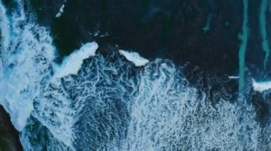 Gök mavisi deniz dalgalarının tropikal adada kum kıyılarıyla buluştuğu tepeden aşağı bir sahne. Renkli su manzarası, yükselen köpük ve kumsal. Renkli doğanın rahatlatıcı bir resmi. Alan ve arkaplan kavramını kopyala