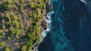 Gök mavisi deniz dalgaları, bol köpüklü kayalar ve ağaçlarla dolu inanılmaz tropikal doğa. Doğal güçlerin gösterimi. Seyahat kavramı. Deniz gelgitlerinin kayalıklara çarpması için muhteşem bir manzara..