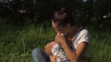 Toplu beslenmenin modern ilerici yaşam tarzı. Annelik kavramı. Parkta emziren bir çocuğun portresi. Duygusal sahnedeki bebek yeşil ağaçlarla çevrili anne göğsünü içiyor..