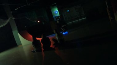 Genç adam rampada paten kayarken dublörlük yapıyor. Millennial, kızlar karanlık stüdyoda izlerken gösteriş yapıyor. Genç, parlayan tekerleklerle numara yapıyor. Yaşam tarzı, etkinlik, sokak kültürü kavramı.