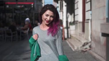 Moda kızı gülümsüyor, poz veriyor ve eğleniyor. Summer City caddesinde yürüyen parlak saçlı neşeli genç bir hipster kadının yakın plan portresi. İnsanlar ve tarz kavramı.