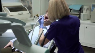 Diş aletlerini kullanarak ağız temizliği. Hasta dişçi muayenehanesinde ağzı açık yatıyor. Stomatolog muayene ediyor ve dişlerle ilgileniyor. Sağlıklı gülümseme kavramı