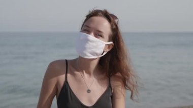 Halka açık yerlerde tıbbi maske takan kadın portresi. Bikinili plaj tatili ve virüs enfeksiyonunu önlemek için koruyucu maske takan çekici, melez bir kadın.
