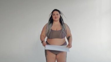 İç çamaşırlı mutlu şişman bir kadın elinde pozitif bir vücut posteri tutuyor. Sweamwer 'daki şişman kız kameraya gülümsüyor. Çeşitli güzellik, çeşitlilik hoşgörü konsepti.