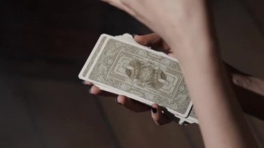 Falcı, ezoterik ayin için tarot kartı hazırlıyor. Dişi mum daireler çiziyor, kartları temizliyor ve enerjiyle doluyor. Kadın kehanet uygulamasından önce, geleceği ve kaderi tahmin etmeye çalışıyor..