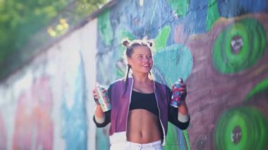 Cesur yaratıcılık ve eğlence. Özgürlük, yaşam tarzı, kültür konsepti. Güzel genç kız sıcak bir yaz gününde havaya sprey püskürtüyor. Yaratıcı sanat. Yetenekli kız öğrenci resim çiziyor.