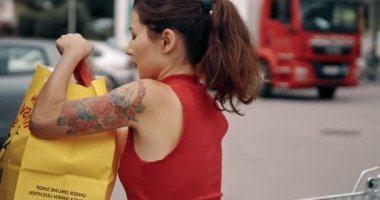 Kadın, arabadan arabaya ürünler yüklüyor. Süpermarketten almak. Gir, dükkândan aldığı çantalarla park yerinde duruyordu. Yalnız başına oldukça Asyalı alışverişi. Satın alma ve satma kavramı, ticaret endüstrisi