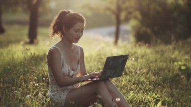 IT uzmanı dışarıda kendini izole ediyor. Kız parkta ya da ormanda oturuyor, doğada dizüstü bilgisayar açıyor. İş yapan ya da doğada serbest çalışan ya da inanılmaz güneş ışığında temiz hava alan bir kadın..
