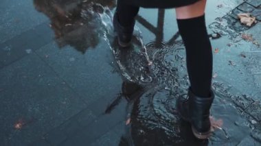 Yağmurlu havada su sıçratan bir kadın. Lastik botlarla şehrin baharının tadını çıkaran kaygısız bir kız. Kadın ayakları şehir havuzunda yürüyor ya da su geçirmez ayakkabılarla su birikintisi yapıyor. Mutluluk kavramı