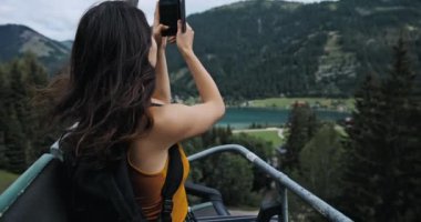 Asansörde yükselirken fotoğraf çeken bir kız. Avusturya 'da seyahat eden güzel bir esmer. Genç bir kadın dağın tepesinde yükseliyor. Yaşam tarzı kavramı, seyahat. faaliyet turizmi.