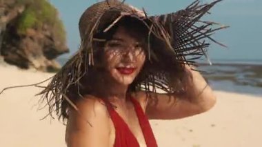 Karışık ırk bayanı tatilini tropikal adada geçiriyor. Bali egzotik atmosferi. Parlak makyajlı güzel Asyalı kadın tropik plajda kırmızı elbiseli dans ediyor. Güzellik, seyahat, moda konsepti ve yaşam tarzı.