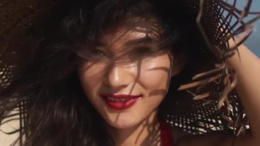 Lüks, şehvetli Asyalı kız portresi kameraya gülümsüyor. Muhteşem bir bakış. Güzelim, seyahat modası. Sıcak yaz günlerinde hasır şapkalı genç, karışık ırk kadını.