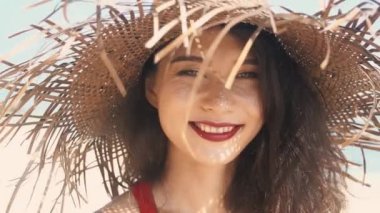 Hasır şapkalı neşeli Asyalı kadın parmaklarının arasındaki kumu elliyor. Kırmızı elbiseli güzel bayan cennet adasının tadını çıkarıyor, güneş parlıyor. Romantik ve sakin bir ruh hali. Bali 'nin seyahat tarzı.