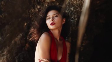 Kırmızı elbiseli, melez bir kadın. Lüks, şehvetli Asyalı kız portresi kameraya gülümsüyor. Sıcak yaz günü, tropik cennet adasında kalırken seksi pozlar. Ticari, müstehcen yaşam tarzı