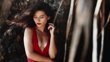 Sıcak yaz günü. Lüks, şehvetli Asyalı kız portresi kameraya gülümsüyor. Kırmızı elbiseli, melez bir kadın. Tropik cennet adasında kalırken seksi poz vermek. Ticari, müstehcen yaşam tarzı