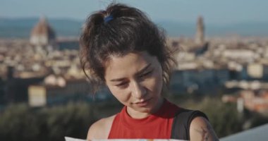 Santa Maria del Fiore 'un arka planında duran şehir haritasına bakan heyecanlı kadın turistin portresi. Yaz tatilinde romantik Floransa 'yı keşfeden esmer kadın profili.