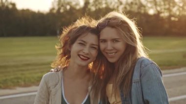 Kadın arkadaşlığı, açık havada yürüyüş. Arka planda klasik güneş ışığı var. Birkaç güzel kız arkadaş, lezbiyen. İki mutlu genç kız birbirine sarılıyor. Kucaklayan, gülen ve heyecanlanan kadınlar..