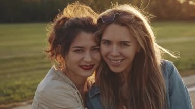 Dişiler kucaklaşır, güler ve heyecanlanır. İki mutlu genç kız birbirine sarılıyor. Kadın arkadaşlığı, açık havada yürüyüş. Arka planda klasik güneş ışığı var. Bir çift güzel kız arkadaş, lezbiyen.