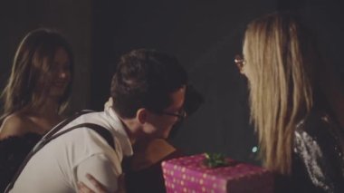 Neşeli bir kadın arkadaşlarıyla kucaklaşıp tokalaşıyor, doğum günü için kağıda sarılmış hediyeler alıyor ve akşam yemeğinden önce evde teşekkür ediyor. Parti ya da doğum günü kutlaması şirket ya da grupla.
