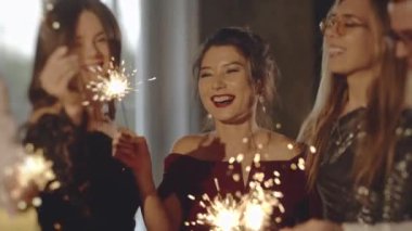 Akşamları eğlenen mutlu bir grup insan. Kapalı portre arkadaşları maytapları ellerinde tutuyorlar. Çocuklar havai fişek sallayarak, yılbaşında ya da Noel arifesinde eğlenerek kutlama yapıyor..