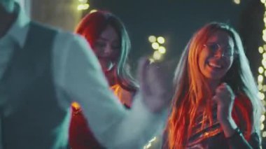 Mutlu, gülümseyen adamlar renkli ışıklarla süslenmiş evin önünde birlikte eğleniyorlar. Doğum gününde, yeni yılda, Noel 'de ya da Xmas partisinde dans eden çok ırklı genç hippi arkadaşlara yakın çekim.