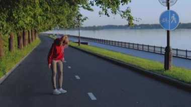 Güzel sarışın koşmadan ya da egzersiz yapmadan önce ısınıyor. Kız rıhtım boyunca koşmadan önce kol ve bacak kaslarını esnetiyor. Karantinada aktif ve sağlıklı bir yaşam tarzı sürdüren atletik kadın.