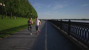 Spor giyimli adamlar sabah kalktıktan sonra koşuyor ya da nehir kenarında koşuyorlar. Esmer adam ve sarışın kız maratona hazırlanıyor. Sağlıklı yaşam tarzı kavramı.