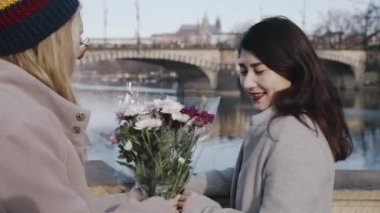 Yakın arkadaşlar nehir kenarında buluşur ve kameranın önünde çiçek buketi değiş tokuşu yapar, birbirlerine sarılırlar. Homoseksüel aile romantik zaman geçiriyor. Lgbt ilişki kavramı.