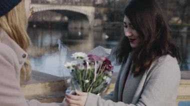 Randevudaki mutlu lezbiyenlerin yakın plan portresi. Sarışın kız Asyalı kız arkadaşına bir demet çiçek veriyor. Genç homoseksüel çift sevgililer gününde birlikte vakit geçiriyorlar. Romantik, LGBTQ konsepti.