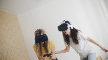 Üç boyutlu teknoloji. Sanal gerçeklik, oyun, arkadaşlık kavramı. Modern sanal gerçeklik kulaklıklarıyla video oyunları oynayan ve birlikte eğlenen iki kadın. Evde kasklı güzel kızlar var..