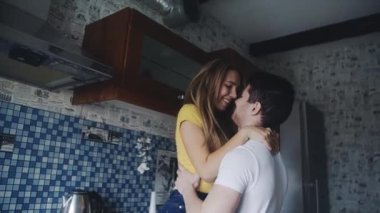 Genç ve güzel bir çift mutfakta tutkuyla öpüşüyor. Seksi genç kız, yakışıklı erkeğiyle birlikte açık renk giyiniyor. Birlikte vakit geçiriyorlar, sarılıyorlar. Aşk kavramı, aile, tutku.