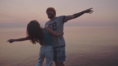 Denizin ortasında duran güzel bir çift kucaklaşması ve öpücüğü. Hippi erkek ve kız gün batımında tatilin tadını çıkarıyorlar. İnanılmaz pembe denizin üzerinde güneş. İzolasyon kavramı