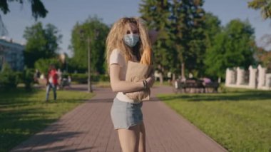 Salgın alışverişi. Karantinadan sonra başka bir hayata alışırsın. Koruyucu maskeli ve eldivenli genç mutlu bir kadın dükkandan eve ürünler taşıyor. Kapsamlı etki konsepti. Yeni gerçeklik.