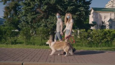 Toplumsal uzaklık. Sevgi dolu bir çift maske takıyor ve şehir parkında bir çoban köpeğiyle yürüyor. Sıcak havanın tadını çıkarıyor. İnsanlar ve hayvanlar konsepti. Keyifli yaz