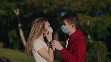 Genç adam ve kadın tıbbi maskeyi çıkarıp öpüşün. Salgın sona erdi. Sonunda karantina sona erdi. Güzel bir çift uzun bir yalnızlıktan sonra buluşur. Sağlık ve tıbbi konsept. Mutlu insanlar..