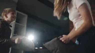 Genç sarışın anne çocuğuyla eğleniyor. Mutlu Avrupalı anne ve genç oğul yastık savaşı ve kendini tecrit ve karantina sırasında yatakta zıplama. Çocukluk, annelik ve aile kavramı.