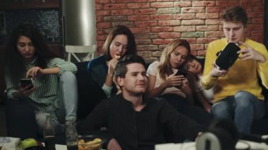 Bir grup genç ev partisinde sıkılıyor. Milenyum kuşakları akıllı telefonlarını, cihazlarını kullanıyor, birbirleriyle etkileşime girmiyorlar. Sosyal etkileşim eksikliği gösteriyor. Sahtecilik, can sıkıntısı, teknoloji kavramı.