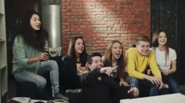 Oturma odasında milenyumlar mutlu ve zaferi sarılarak ve çığlık atarak kutluyorlar. Bir grup genç televizyonda spor müsabakalarını heyecan ve tezahüratla izliyor. Eğlence anlayışı, yaşam tarzı, televizyon..