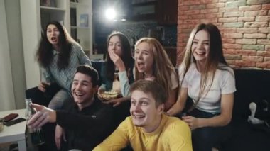 Bir grup genç televizyonda spor müsabakalarını heyecan ve tezahüratla izliyor. Oturma odasında milenyumlar mutlu ve zaferi sarılarak ve çığlık atarak kutluyorlar. Eğlence anlayışı, yaşam tarzı, televizyon..