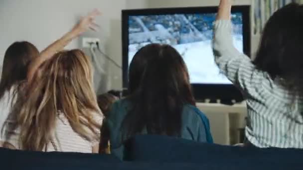 Backshot skupina teenagerů sledujících hokejový zápas v televizi slaví gól. Nadšené milénia povzbuzující tým sedí v obývacím pokoji. Koncept volného času, životního stylu, trávení času spolu, vítězství.