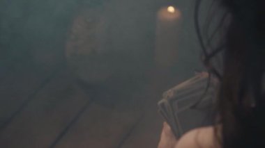 Gizemli ayine hazırlanan tarot kartları karıştıran bir kadın. Falcı, Odrer 'e gizli kehanet ayini için kart koyuyor. Gizem ve Cadılar Bayramı atmosferi mum ve dumanla güçlendirilir..